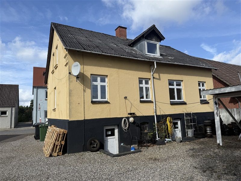 Danmark, Gadbjerg. Højhus med mange vinduer, satellitskål, brædder, slanger og affaldsposer. Lysblå himmel med skyer.