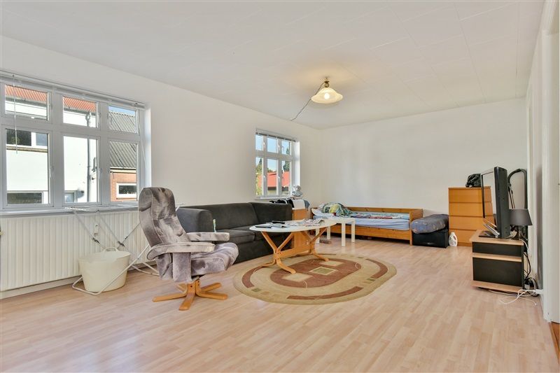 Lejlighed med en lukket stue og to soveværelser, hvor der er spisestue med træbord og sofa samt en satellit og skabe