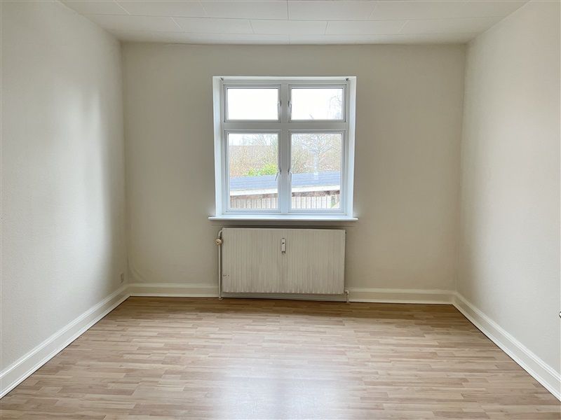 Tom lejlighed med højloft, hvidt panel og trægulv i Gadbjerg. Lejligheden har vinduesfelt med moderne plastruder.