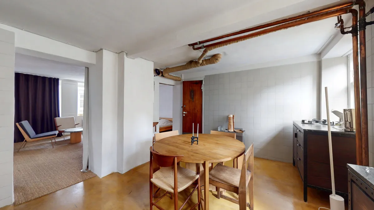 Et moderne køkken med lyse træskabe og en gulv i træ og et bord med fire stole samt lysegule vægge