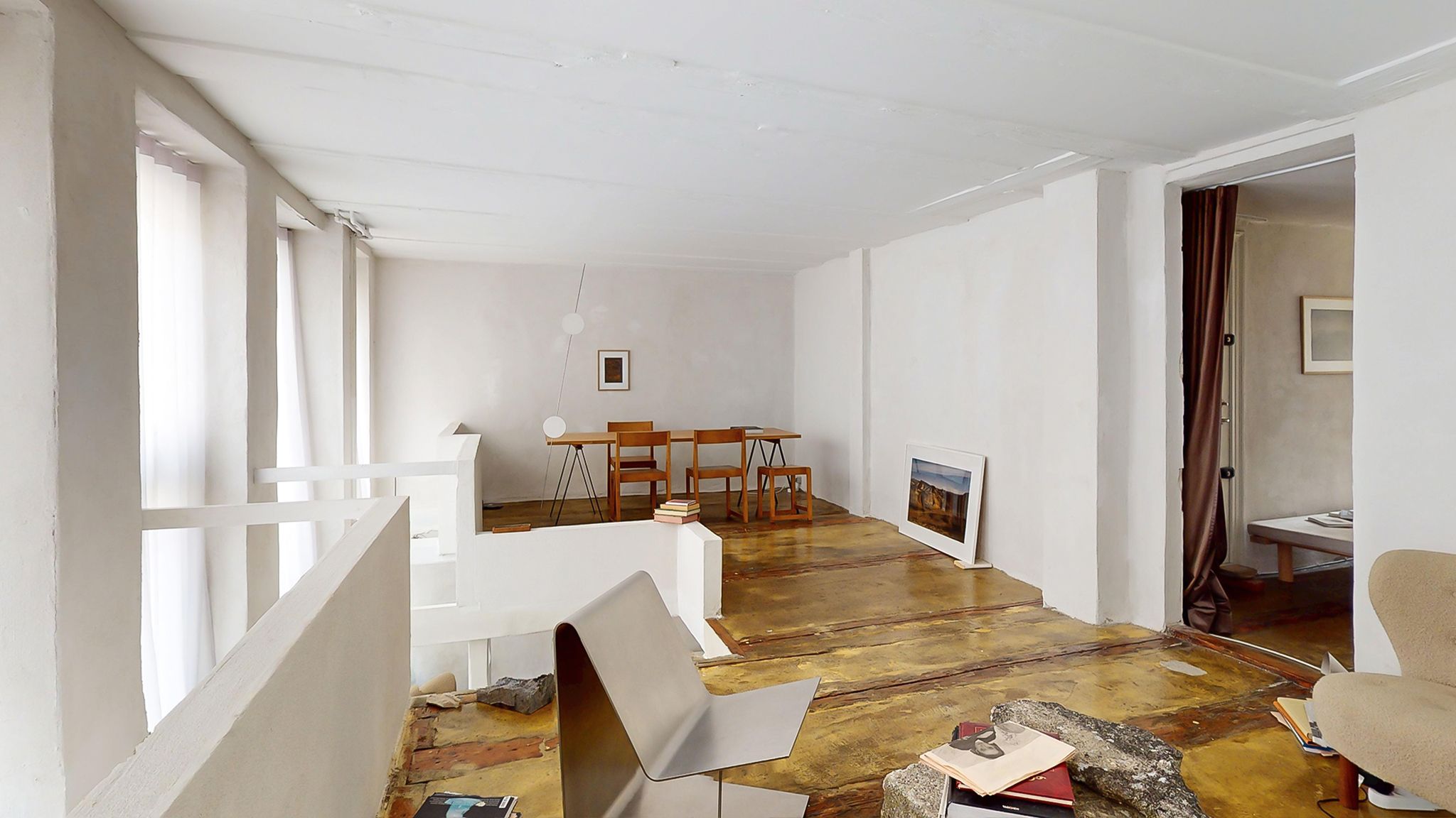 Et veludstyret rum med lyse hvide vægge og en trægulv med bøjler og stole i enden af værelset samt et ståbord og stole