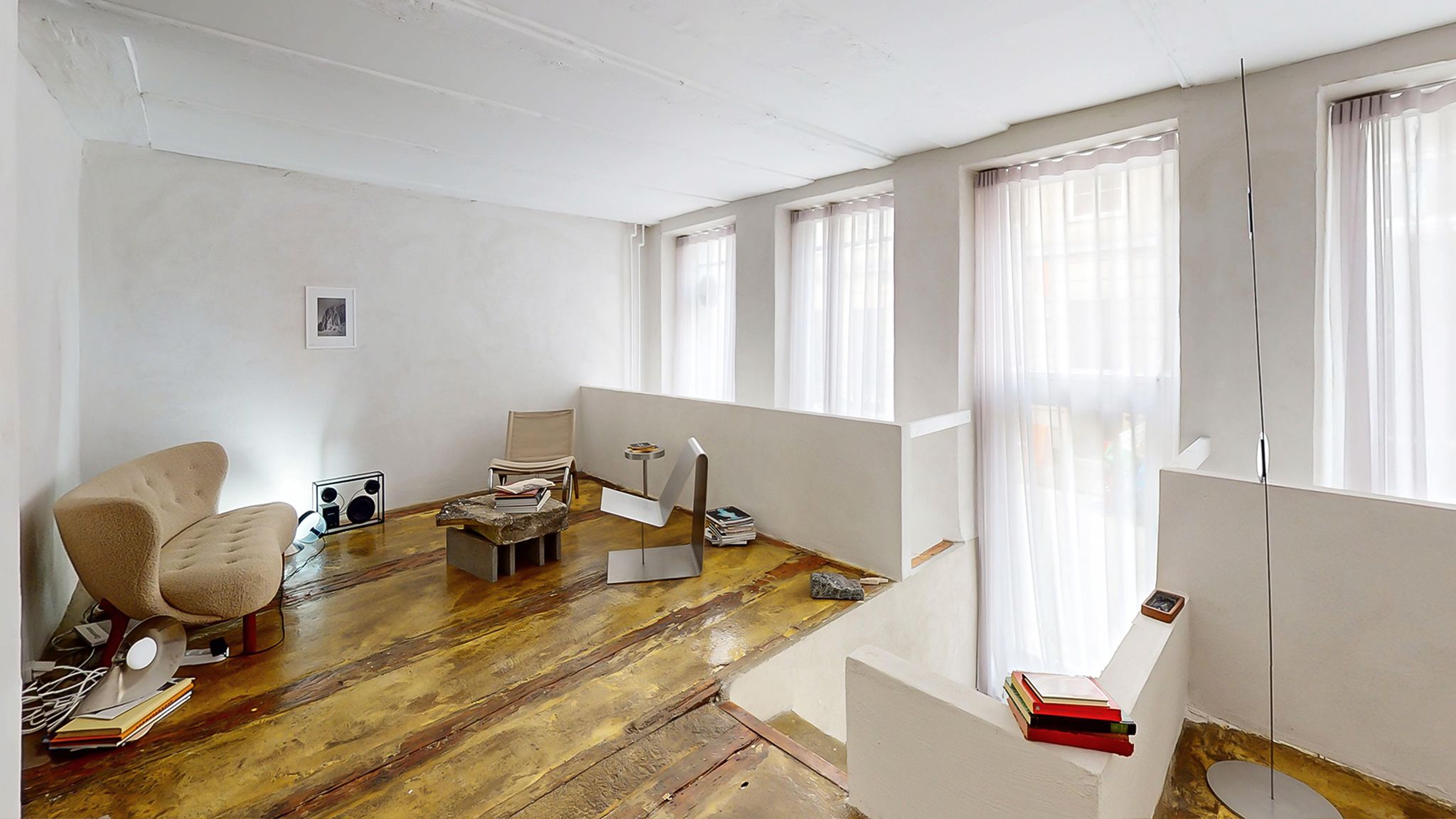 Rå stue med møbler og lysegardiner, og gulvtæppe med flere genstande og udstyr på gulvet og i nærheden af væggen