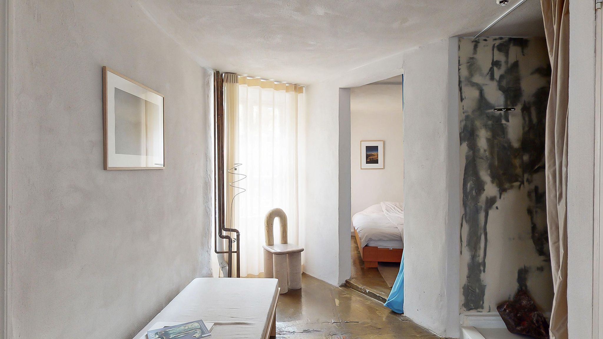 Råt hvidt loft og vægge i en minimalistisk rumindretning med en hvid stol og en sofa i et soveværelse med en skandinavisk