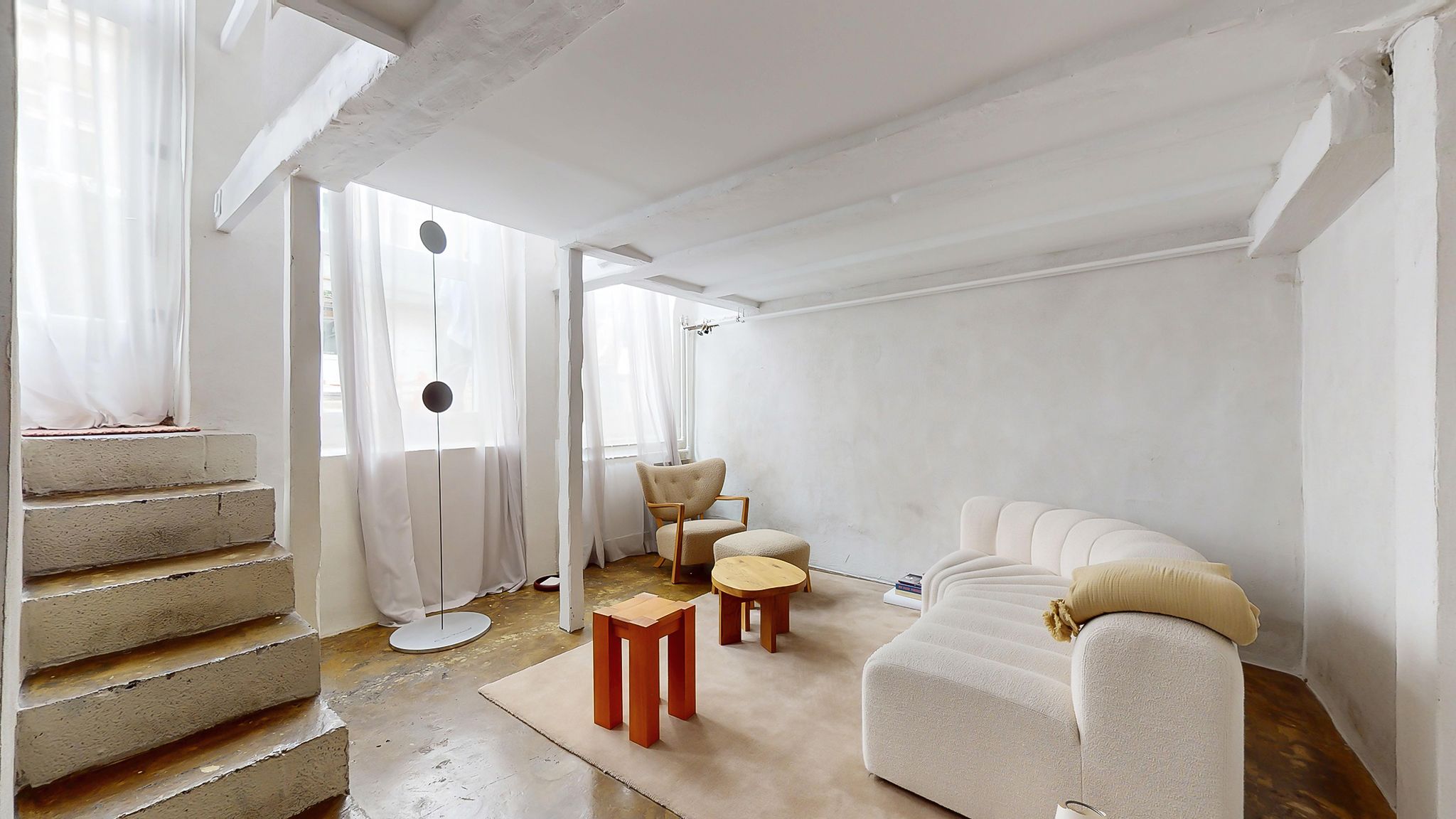 Moderne og minimalistisk værelse med hvid væg og trægulv, sofa, bord og stol, samt loft med hvide bælge og loftsvinduer med