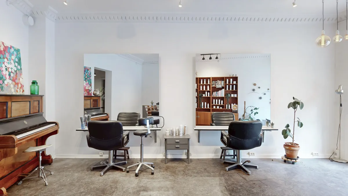 Et moderne interiør med to stolpestationer med spejle og stolpe. To stolpestationer med høje stolen og bord. Et træskab med