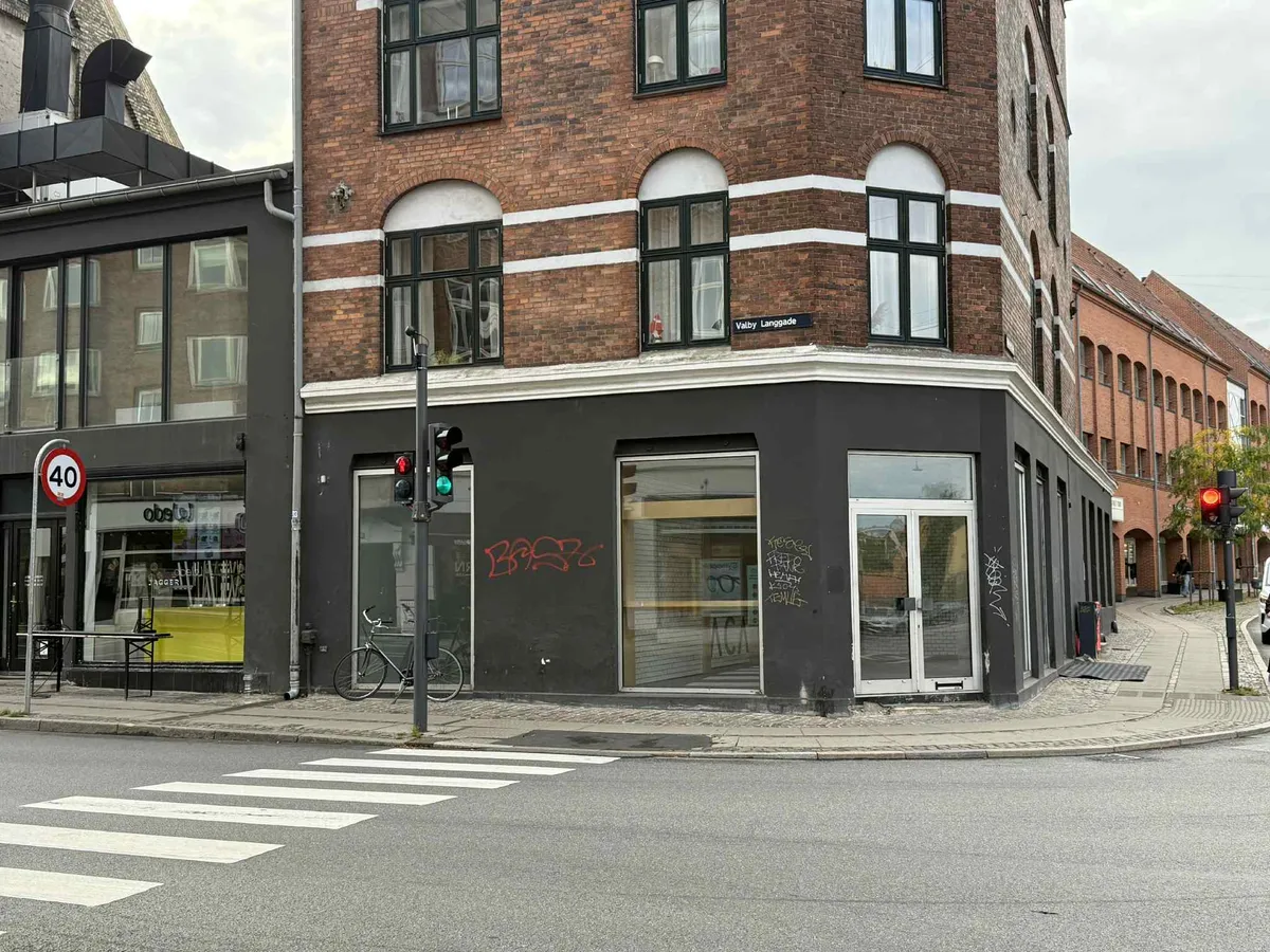 Bryggeriets facade med graffiti og skiltet Valby Langgade, torvet med gågade og cykel, kryds med zebraoverskæring og