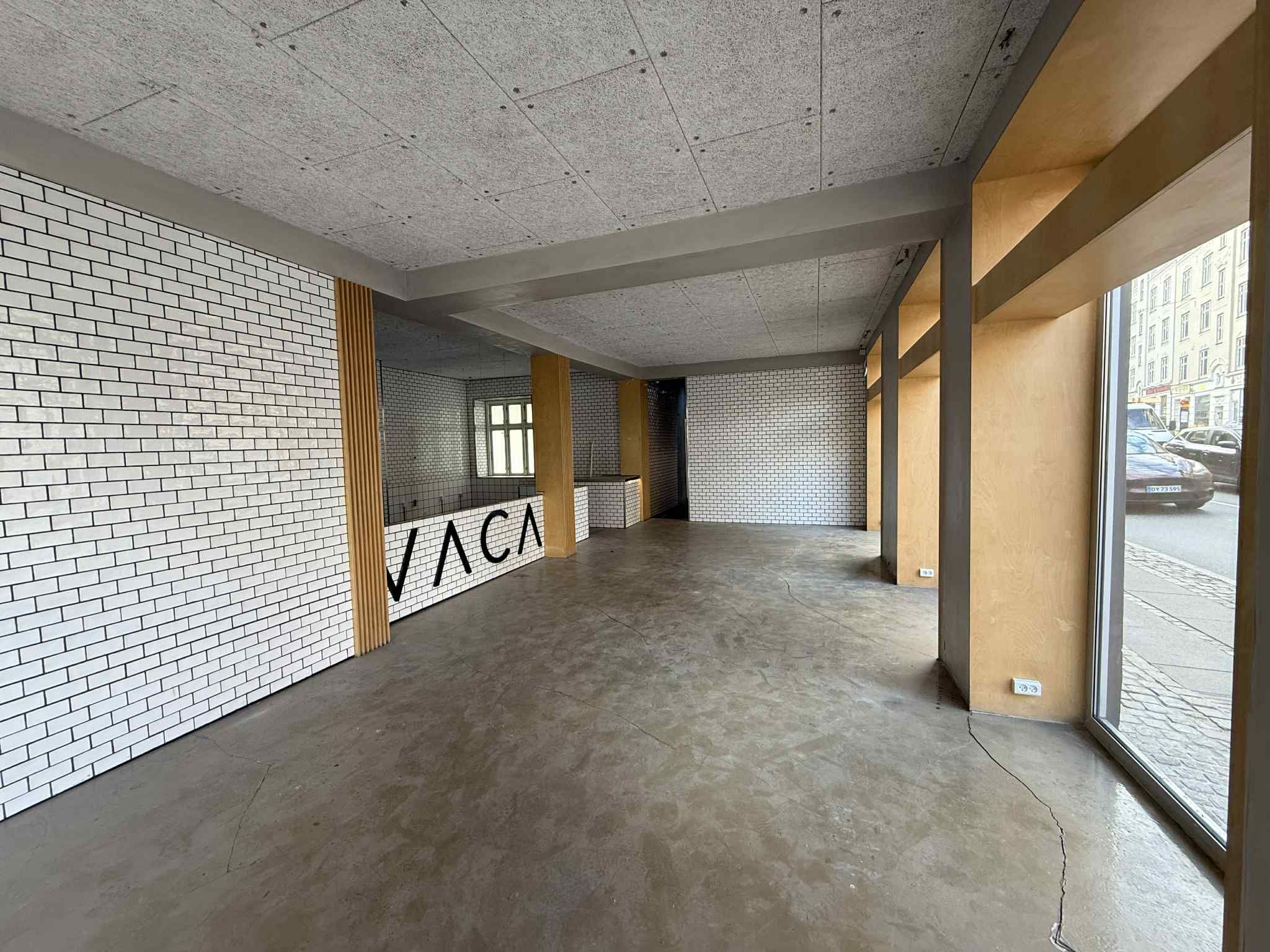 Valby erhvervslejemål med hjørneplacering, hvidt murværk, gulv og loft, møbler og tekst på væggen