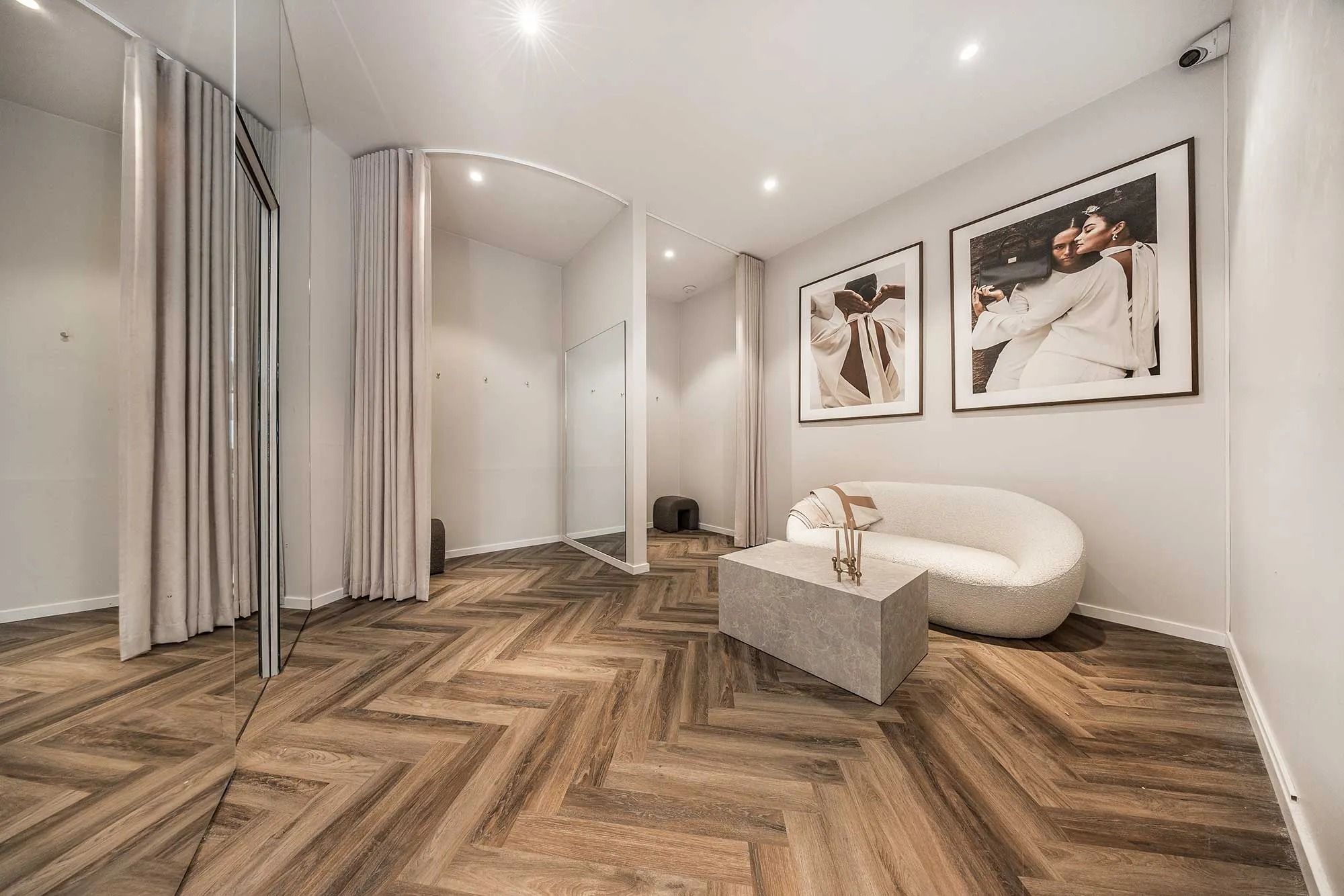 Elegant indrettet lobby med massivt trægulv, hvid sofa og to store billeder på væggen