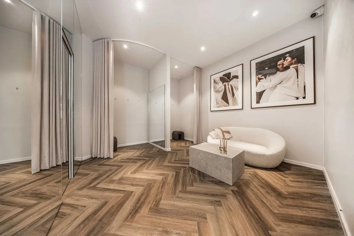 Elegant indrettet lobby med massivt trægulv, hvid sofa og to store billeder på væggen