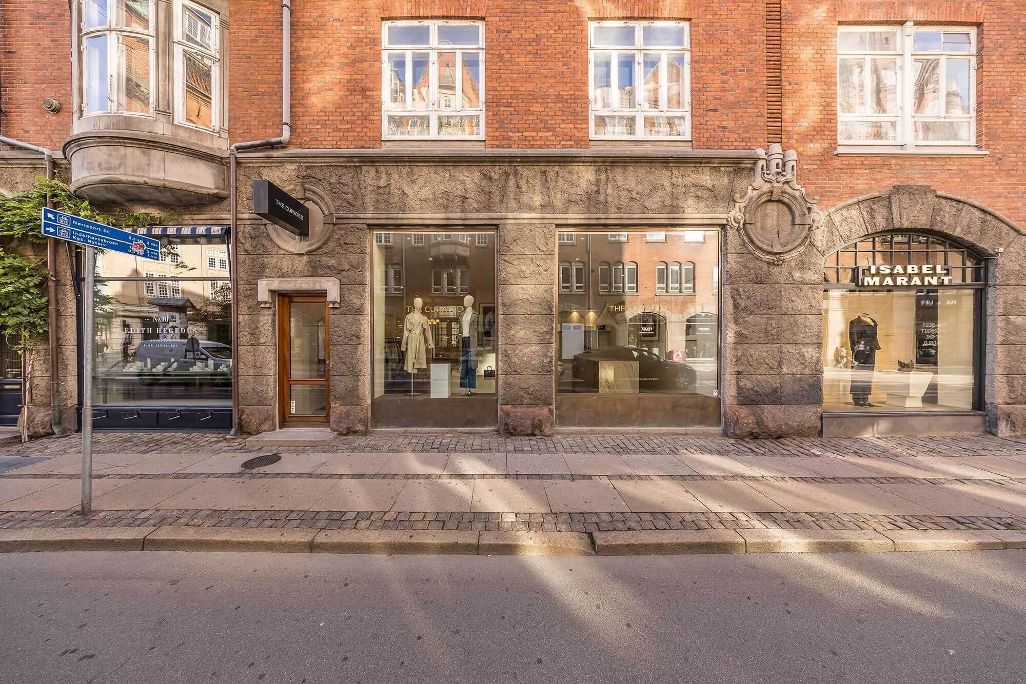 En smukt indrettet butikslejemål på Christian IX’s Gade med elegant facade og vinduer viser modeartikler i udsagnet