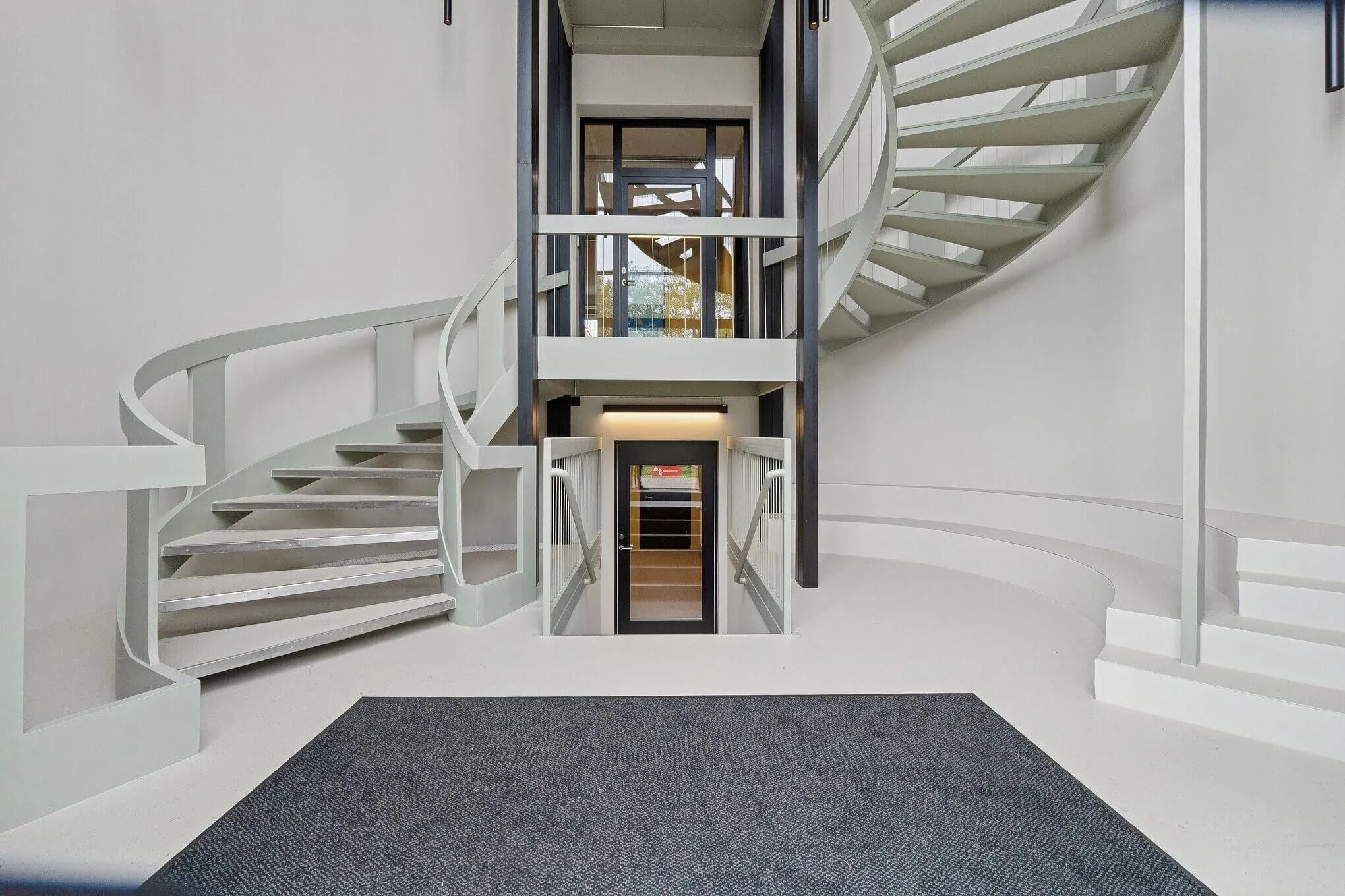 Moderne og minimalistisk trappe op til stueetagen med elevator og lyse gulve i hvidt