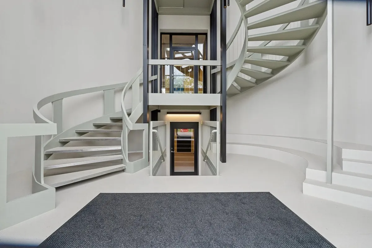 Moderne og minimalistisk trappe op til stueetagen med elevator og lyse gulve i hvidt