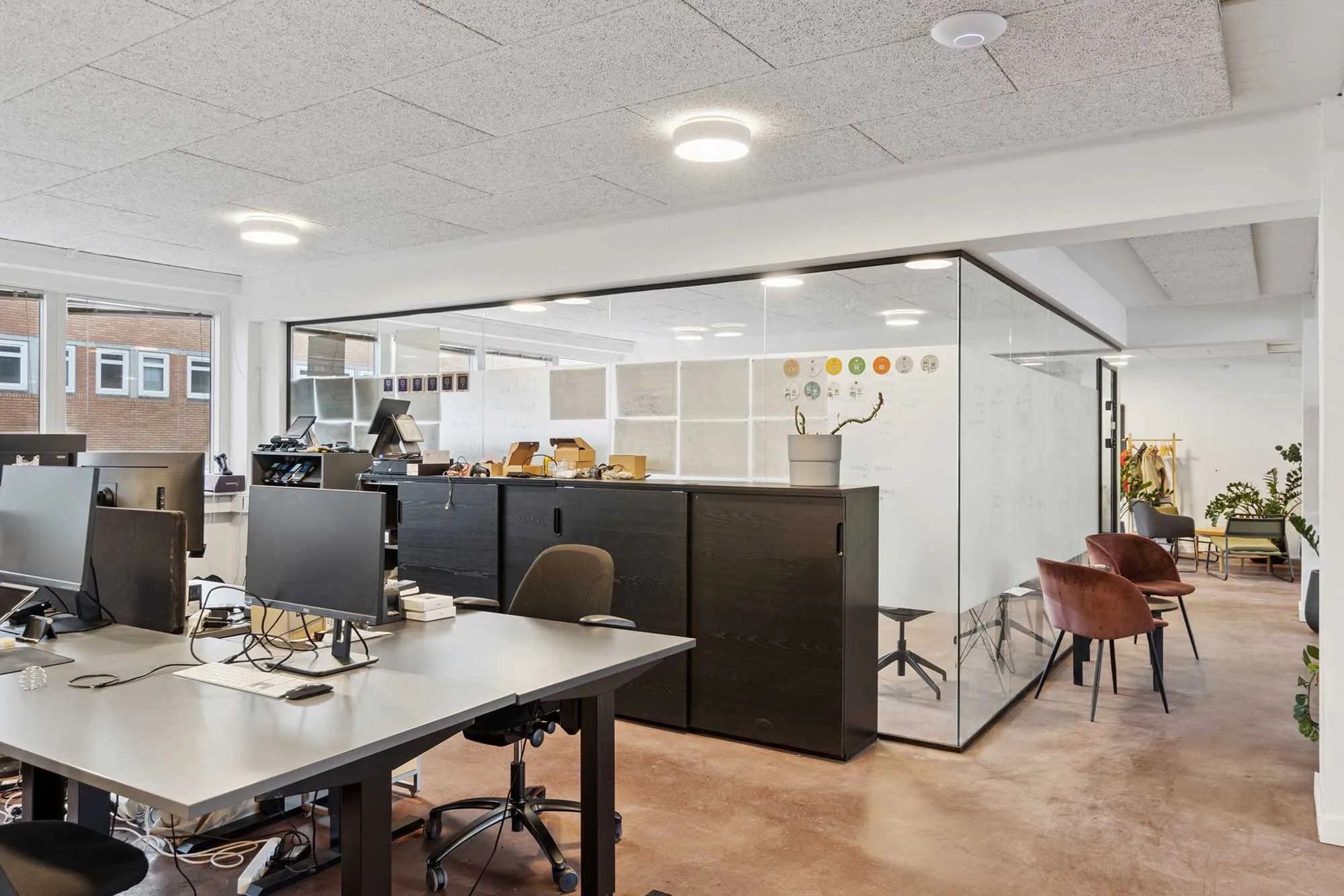 Kontor med lyse hjørner og lyse loftslamper, moderne skriveborde, og møbler, der giver en behagelig arbejdsplads