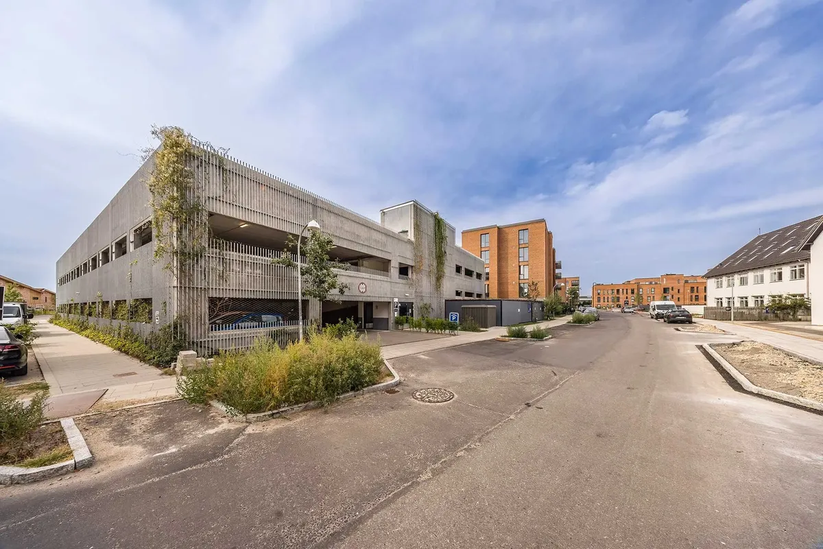 Moderne kontorejendom med parkeringsgarage, hvor grønne planter dækker væggene og taget