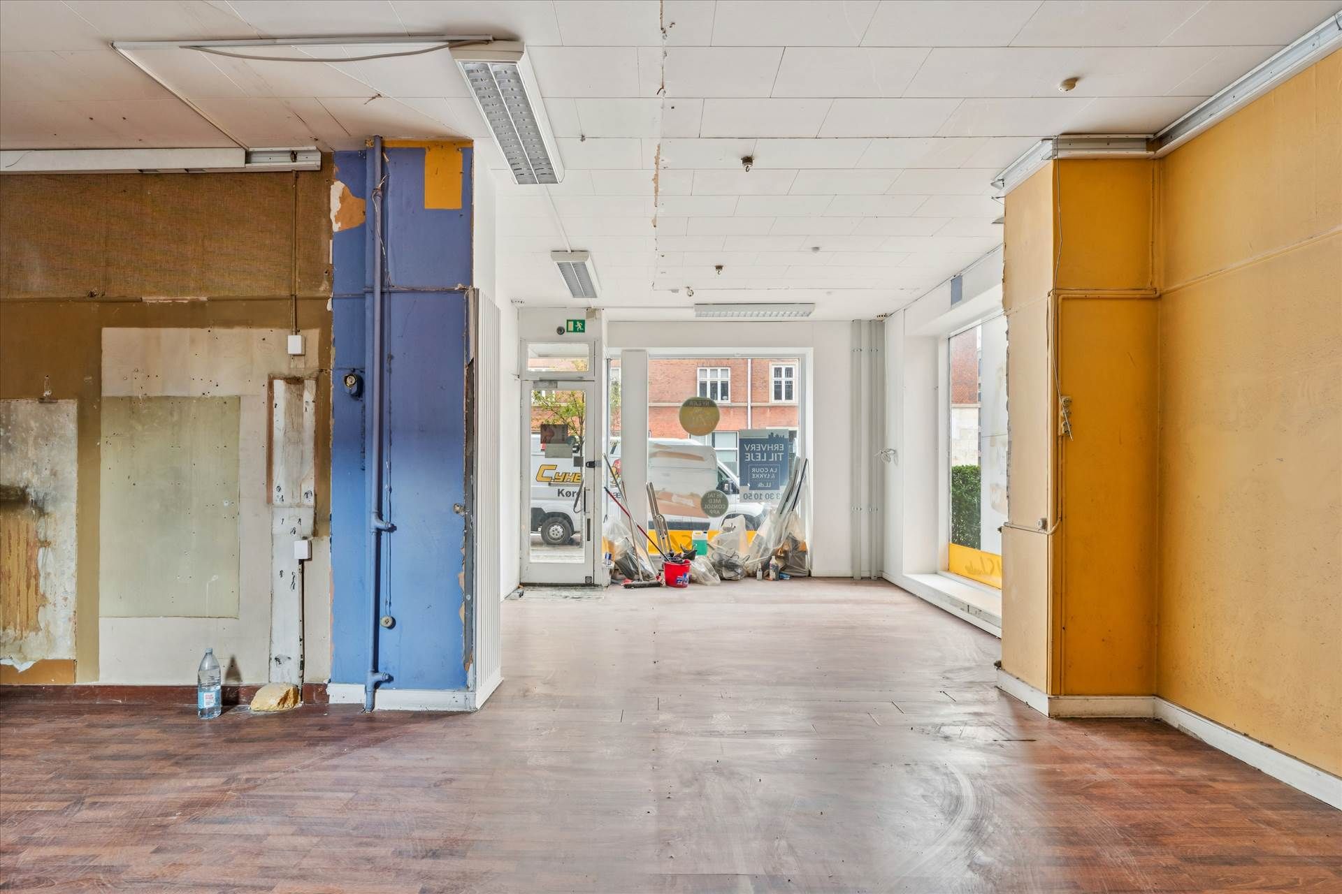 En tom lejlighed med åben dør og et højre gulv og væg i gul og blå farve.