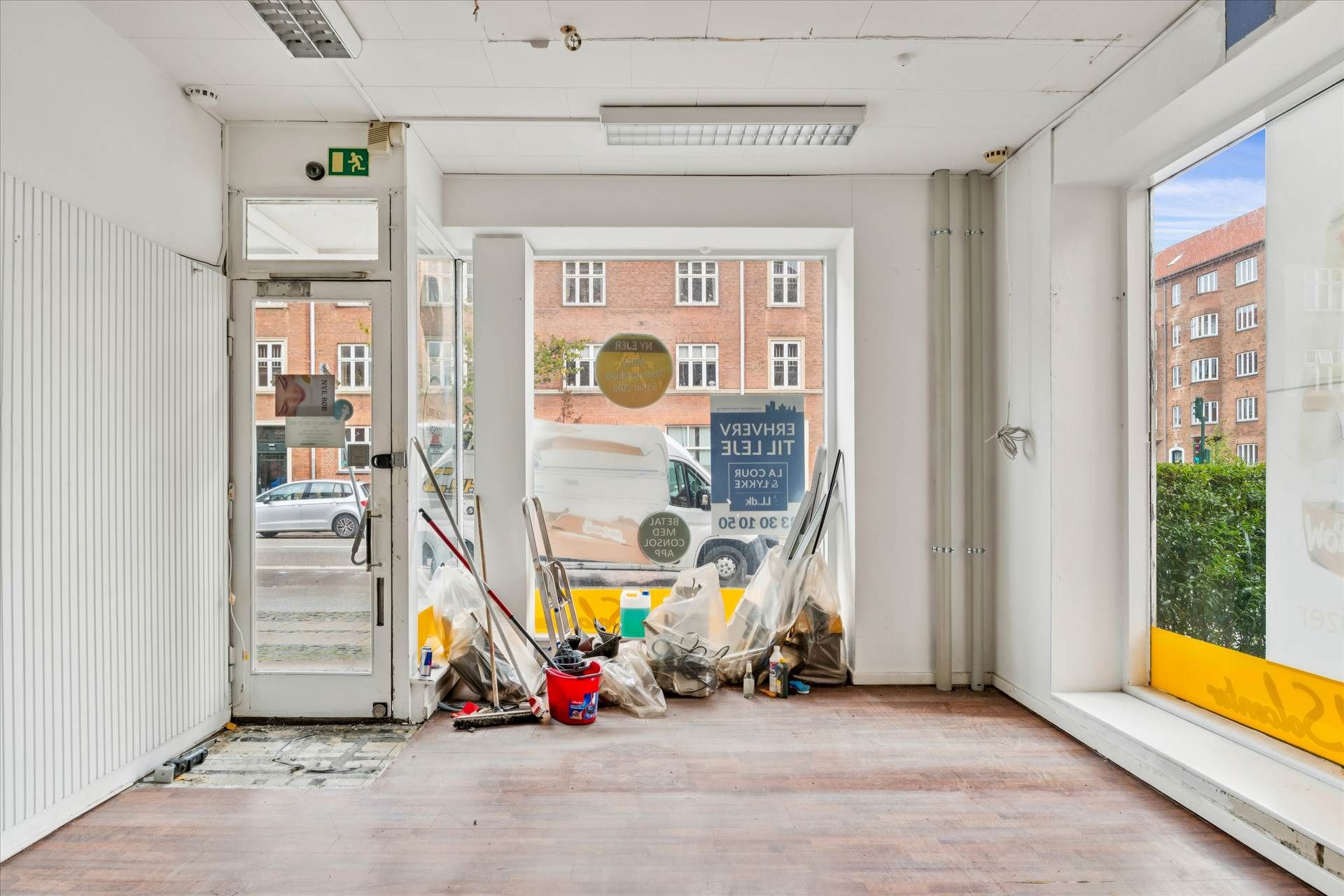 Et åbent erhvervslejemål med glasdøre og vinduer og en ren gulvoverflade samt våd gulvvedligeholdelse og støvsuger