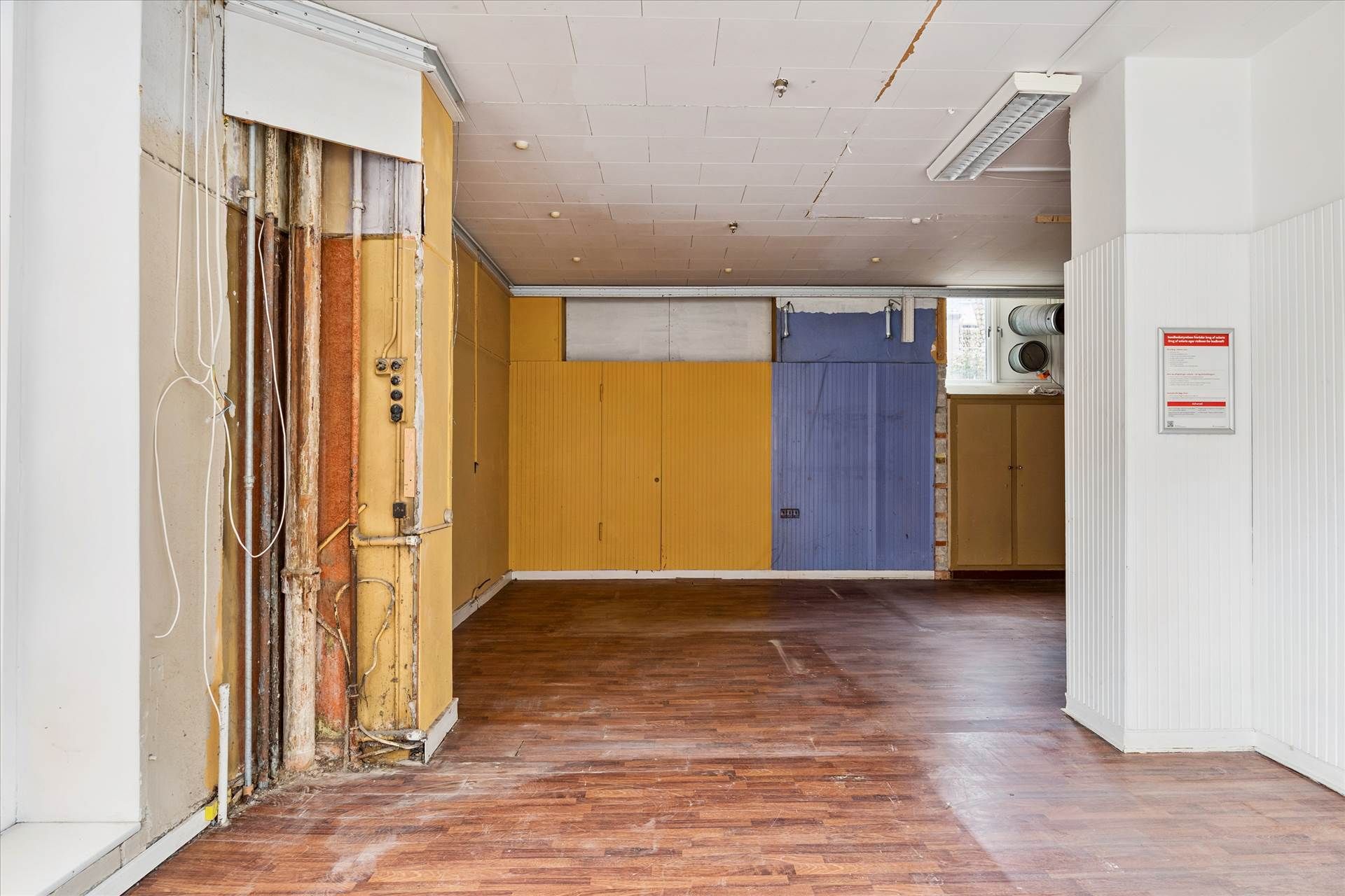 Et renoveret lokale med delvist færdigt loft og gulv og udstykninger i blåt og gult