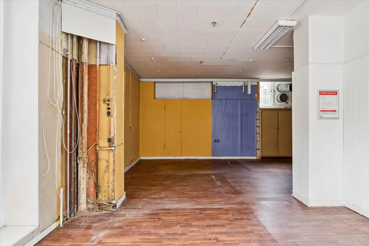 Et renoveret lokale med delvist færdigt loft og gulv og udstykninger i blåt og gult