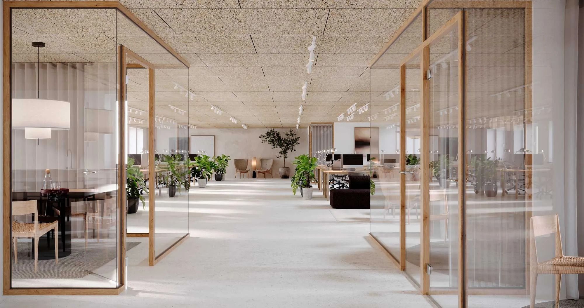 En moderne kontorbygning med hvide vægge, glasvinduer og lysegulve, hvor der er flere bord og stole samt flere smukke planter