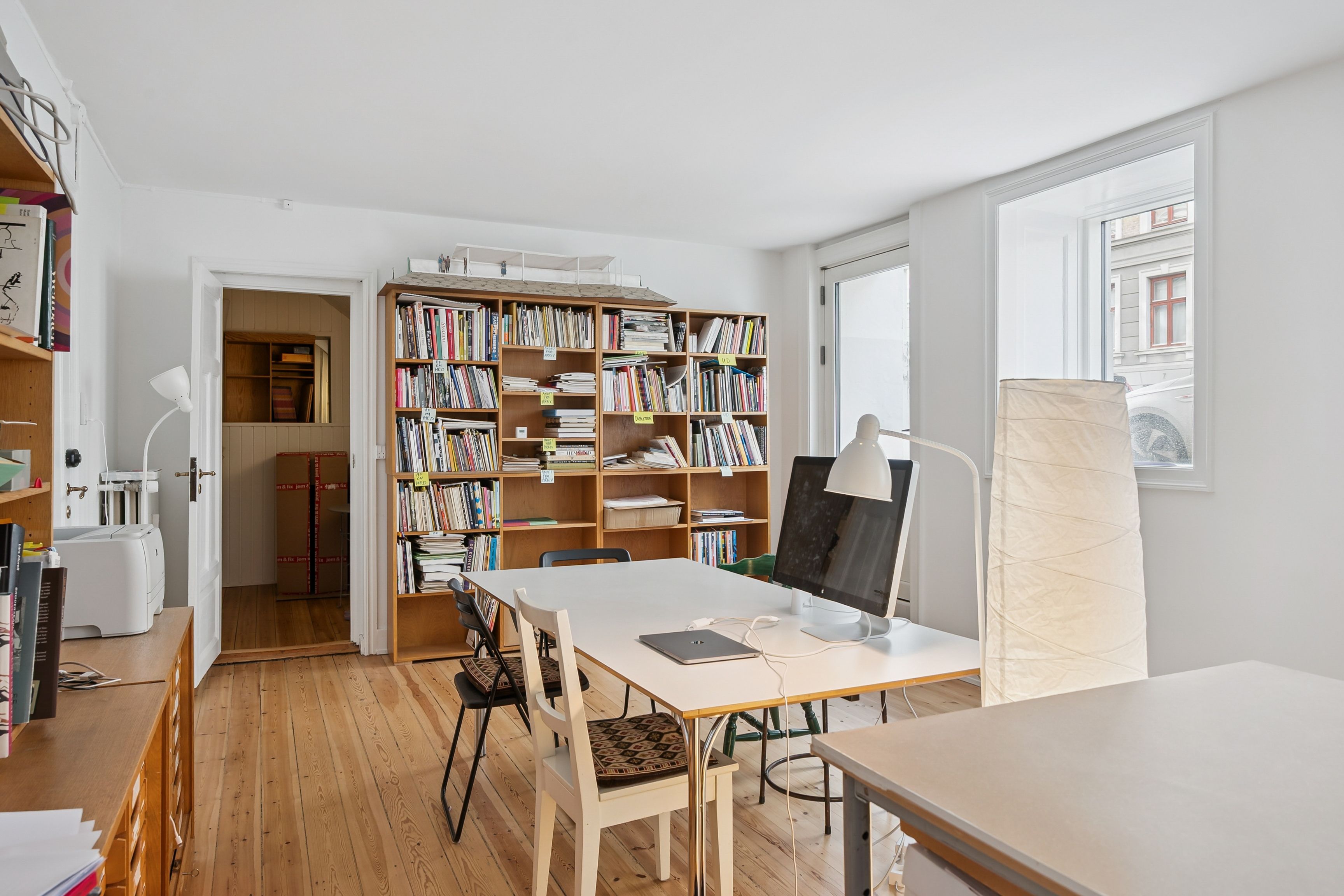 Moderne kontorlokale med højt kvalitetsmæssigt udstyr og møbler, herunder en stor bogreol, skrivebord og computere