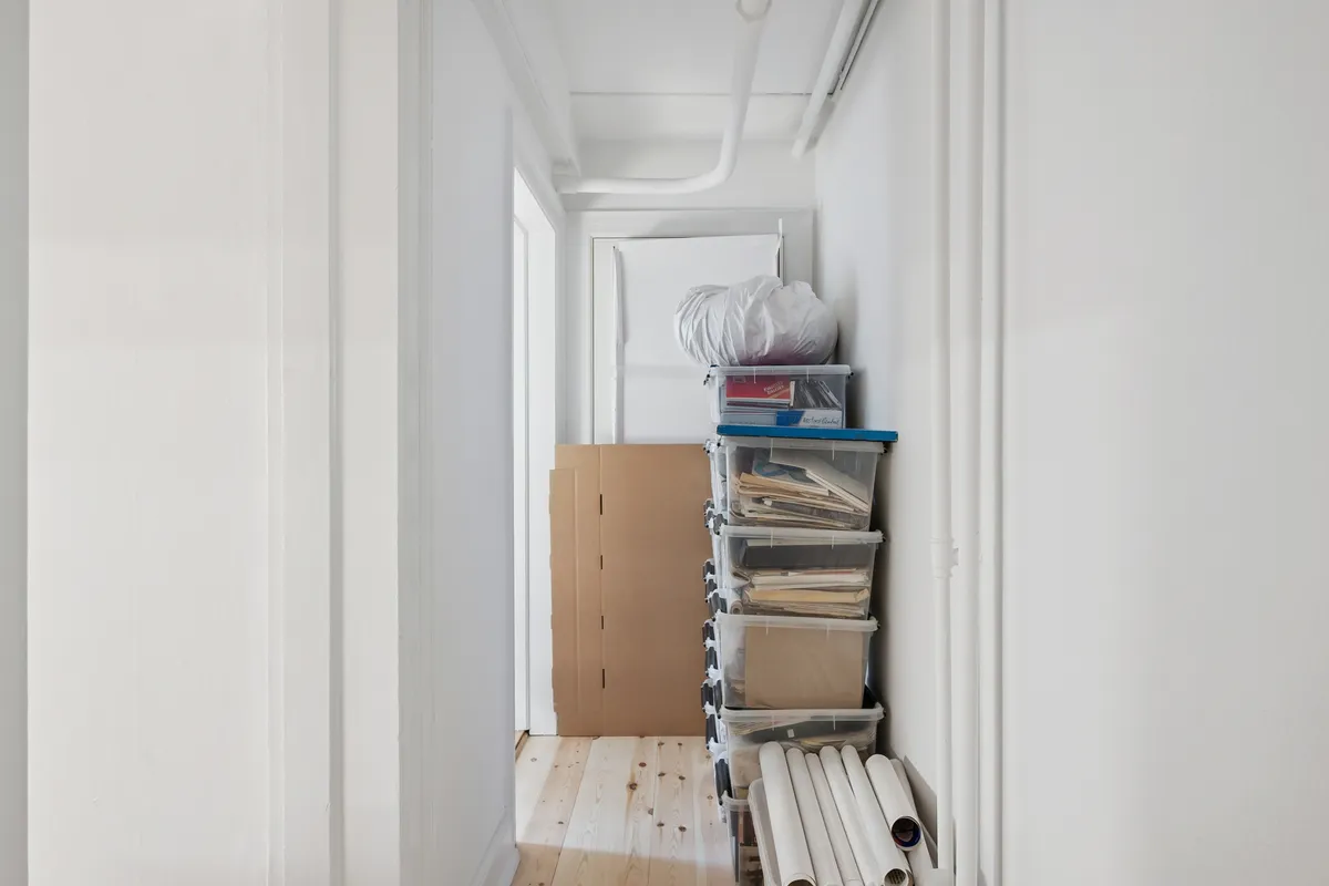Ledig kælderlokale med flere lagerkasser, papkasser og plastposer. Kælderlokale har hvide vægge og trægulv