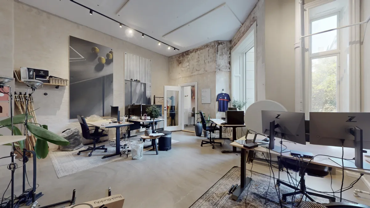 Kæmpe kontorlokaler med lyse gulve og flere skriveborde med moderne computere og lysekroner