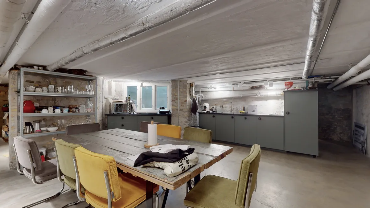 Underjordisk køkken med rustik indretning og massivt bord, opbevaringsskabe og lysekroner i loftet