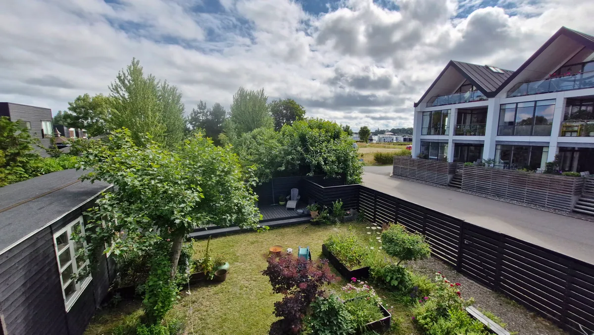 En smuk have med planter og blomster samt en terrasse med en stol og en træhylde