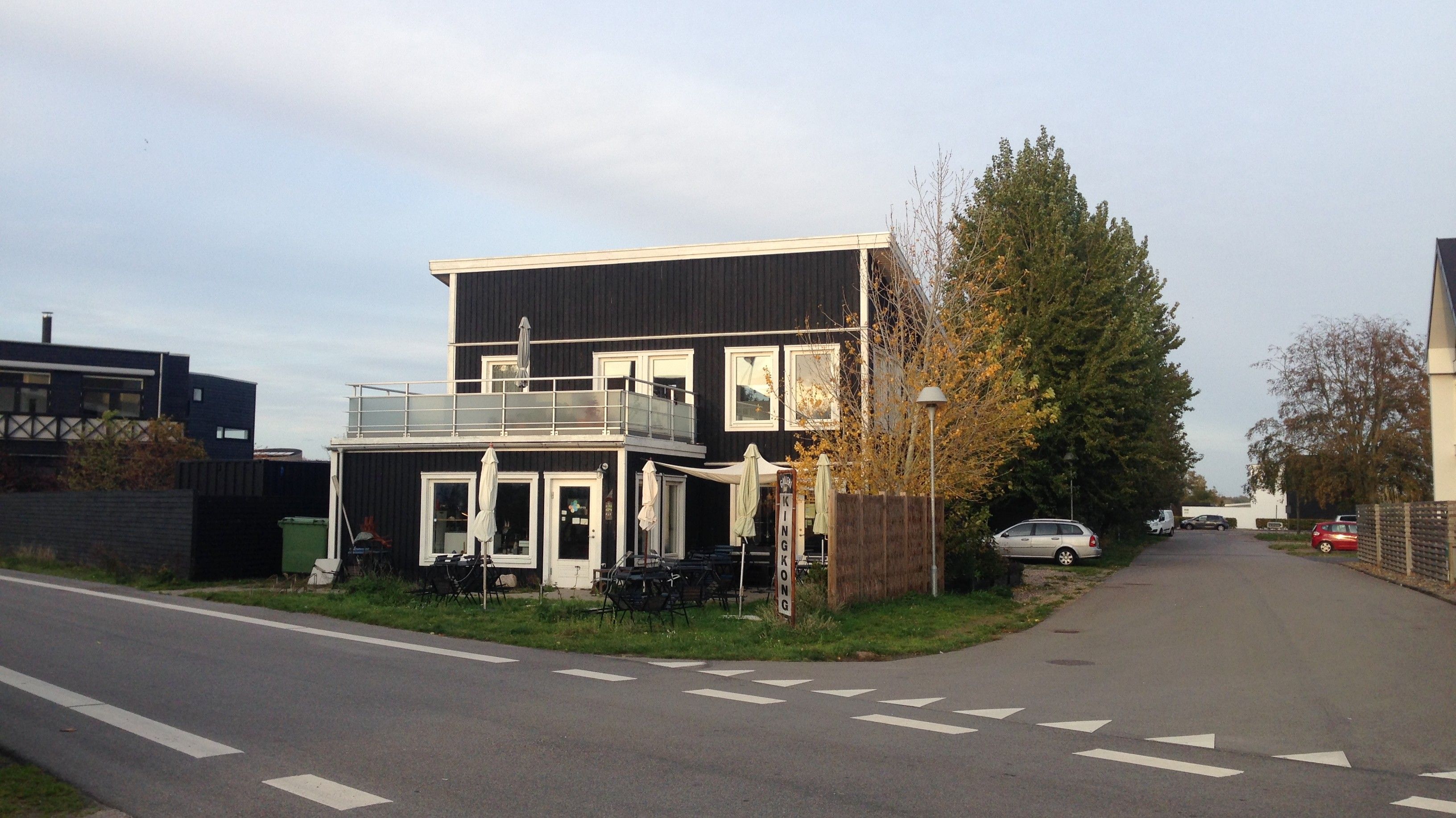 Et moderne bolig- og erhvervsbyggeri med balkon, terrasse og møbelsæt i udkanten af byen