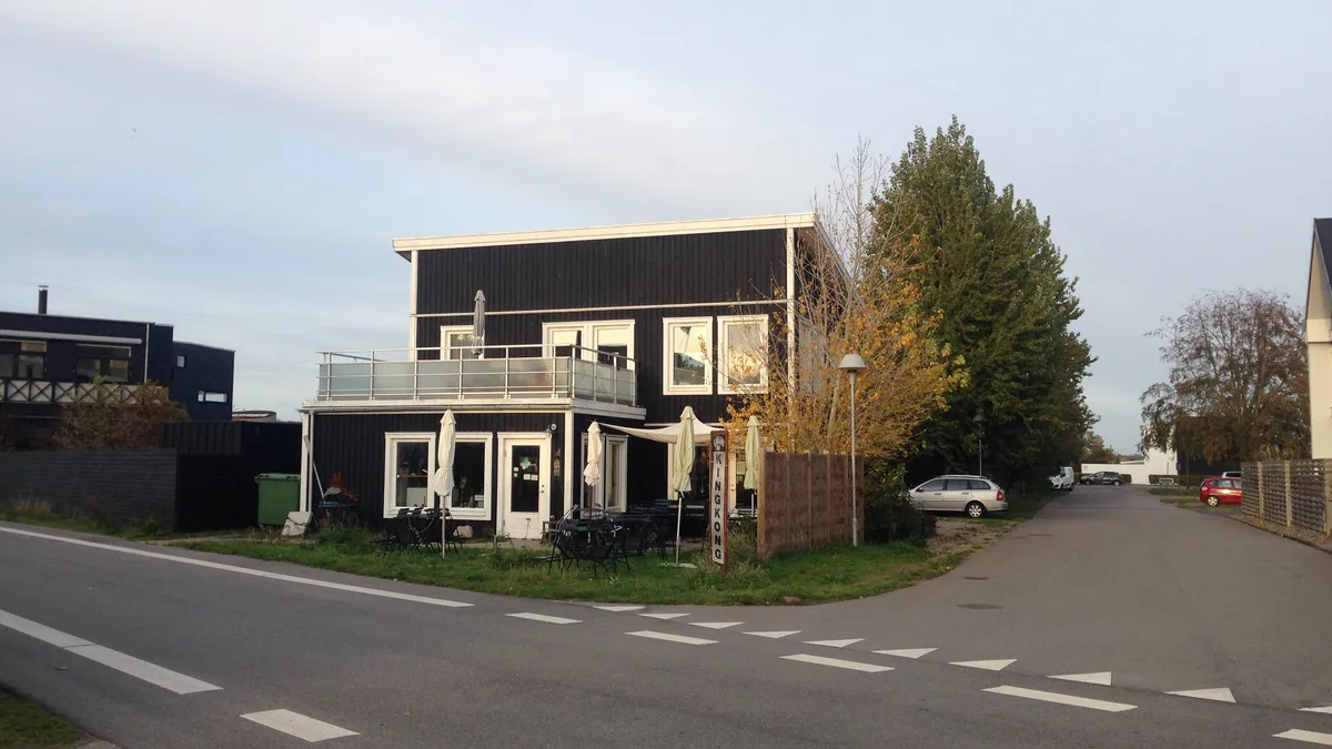 Et moderne bolig- og erhvervsbyggeri med balkon, terrasse og møbelsæt i udkanten af byen