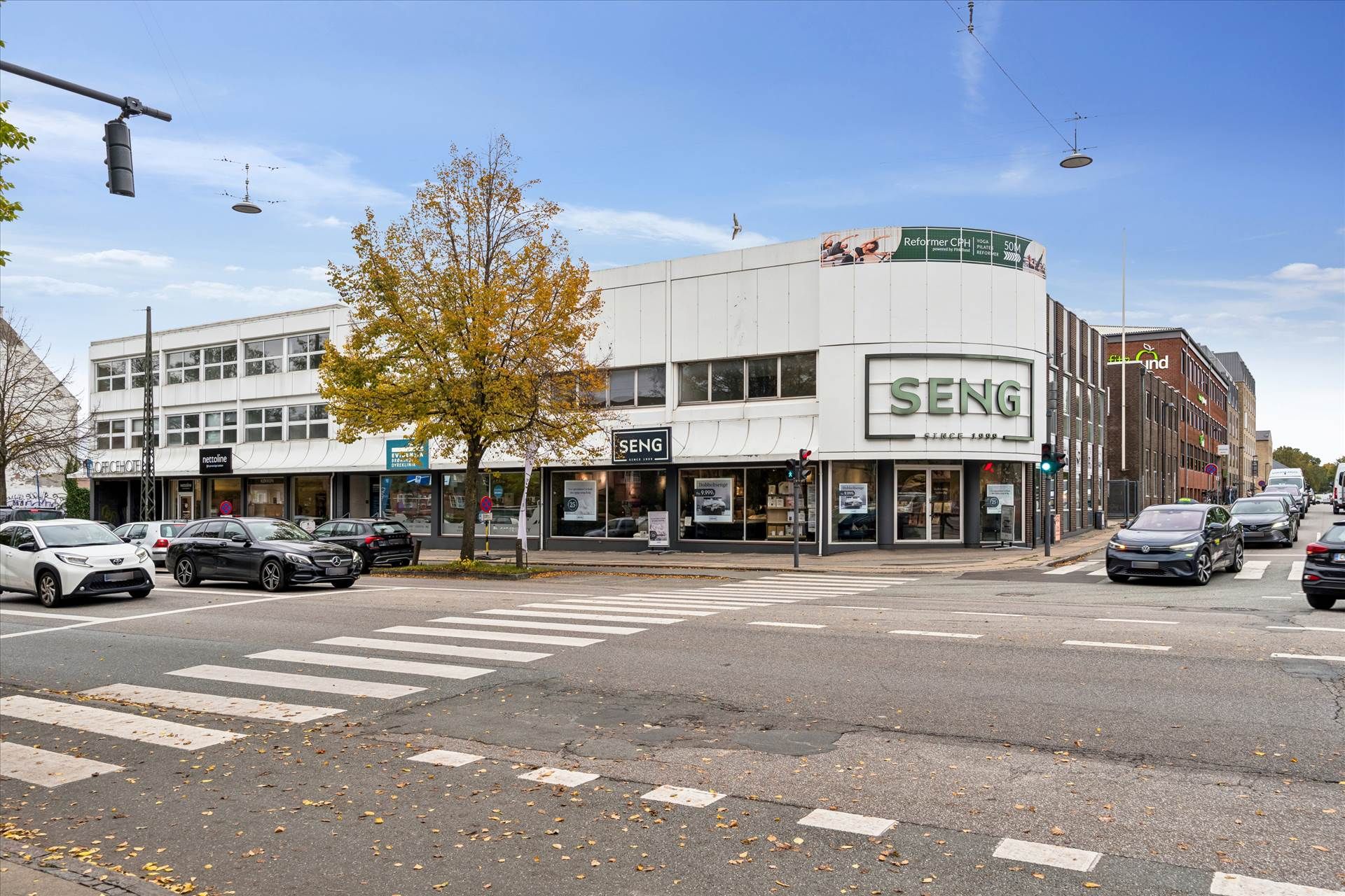 Bygning med Seng-skilt og reformer yoga på facaden og Husumvej Frederikssundsvej-krydset med biler og trafiklys