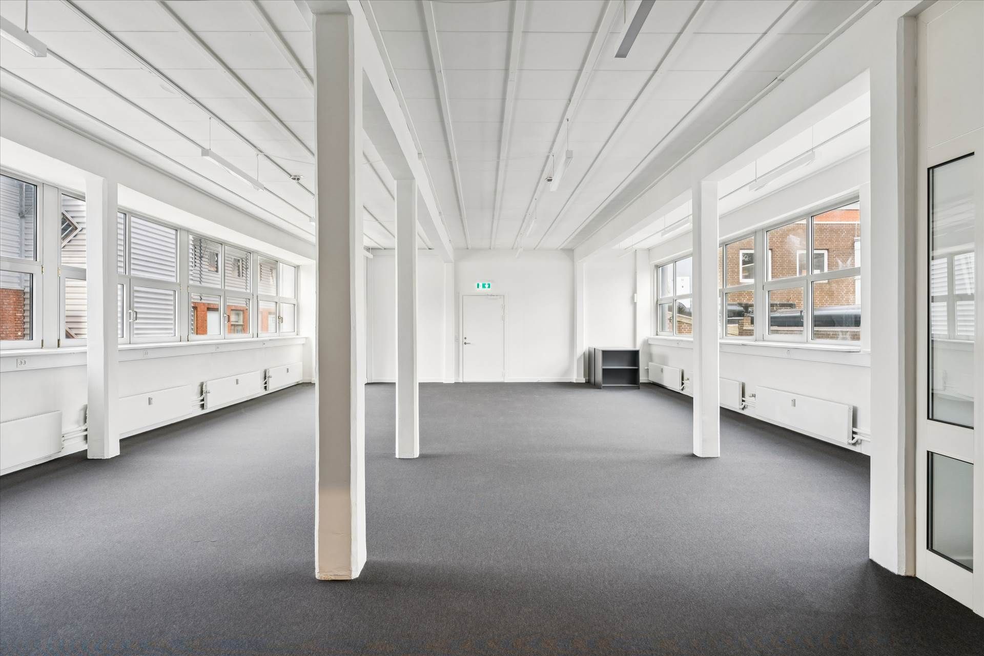 Række af kontorlokaler med store vinduer og højt gulv til leje i Frederikssundsvej, Husumvej. Lokalerne har hvide vægge,