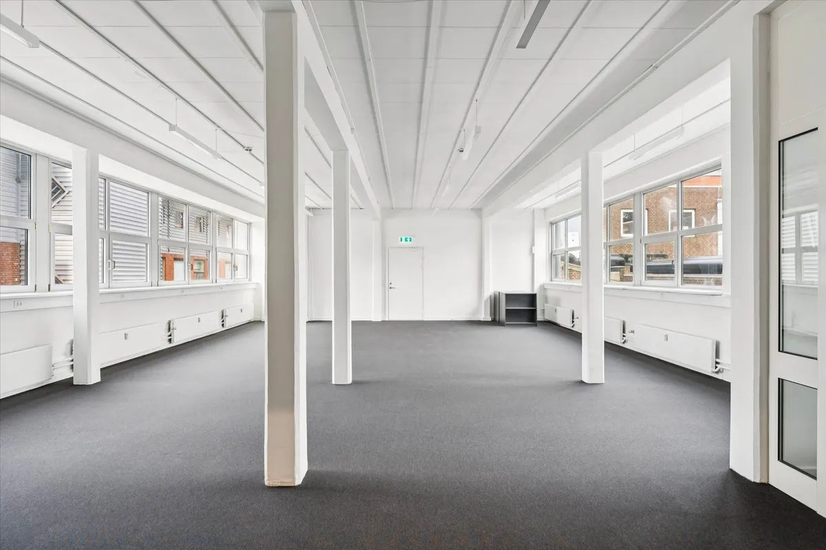 Række af kontorlokaler med store vinduer og højt gulv til leje i Frederikssundsvej, Husumvej. Lokalerne har hvide vægge,