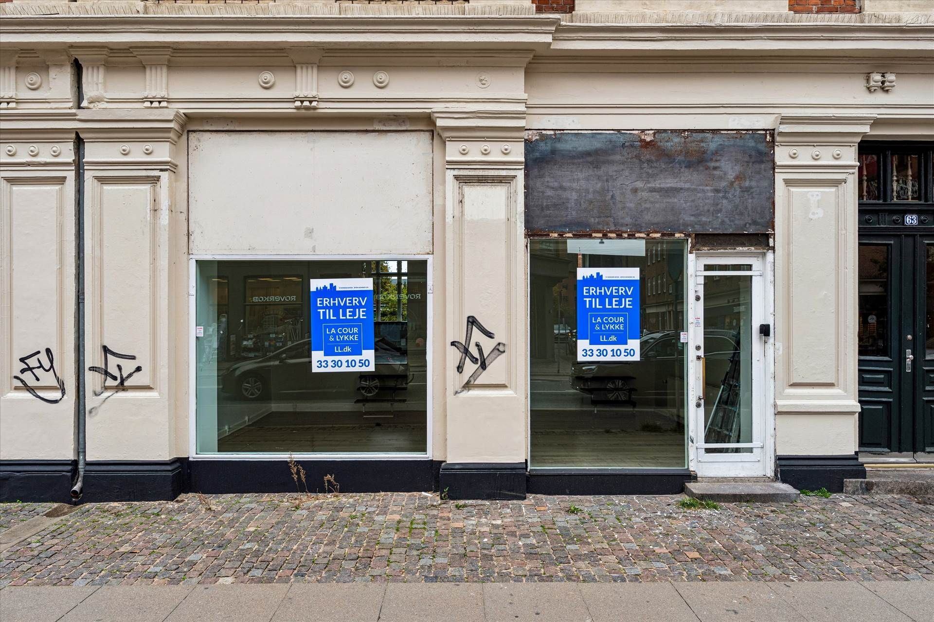 Butik med udsalgsvindue med skilte og åbent indgangsdør med nummer 63