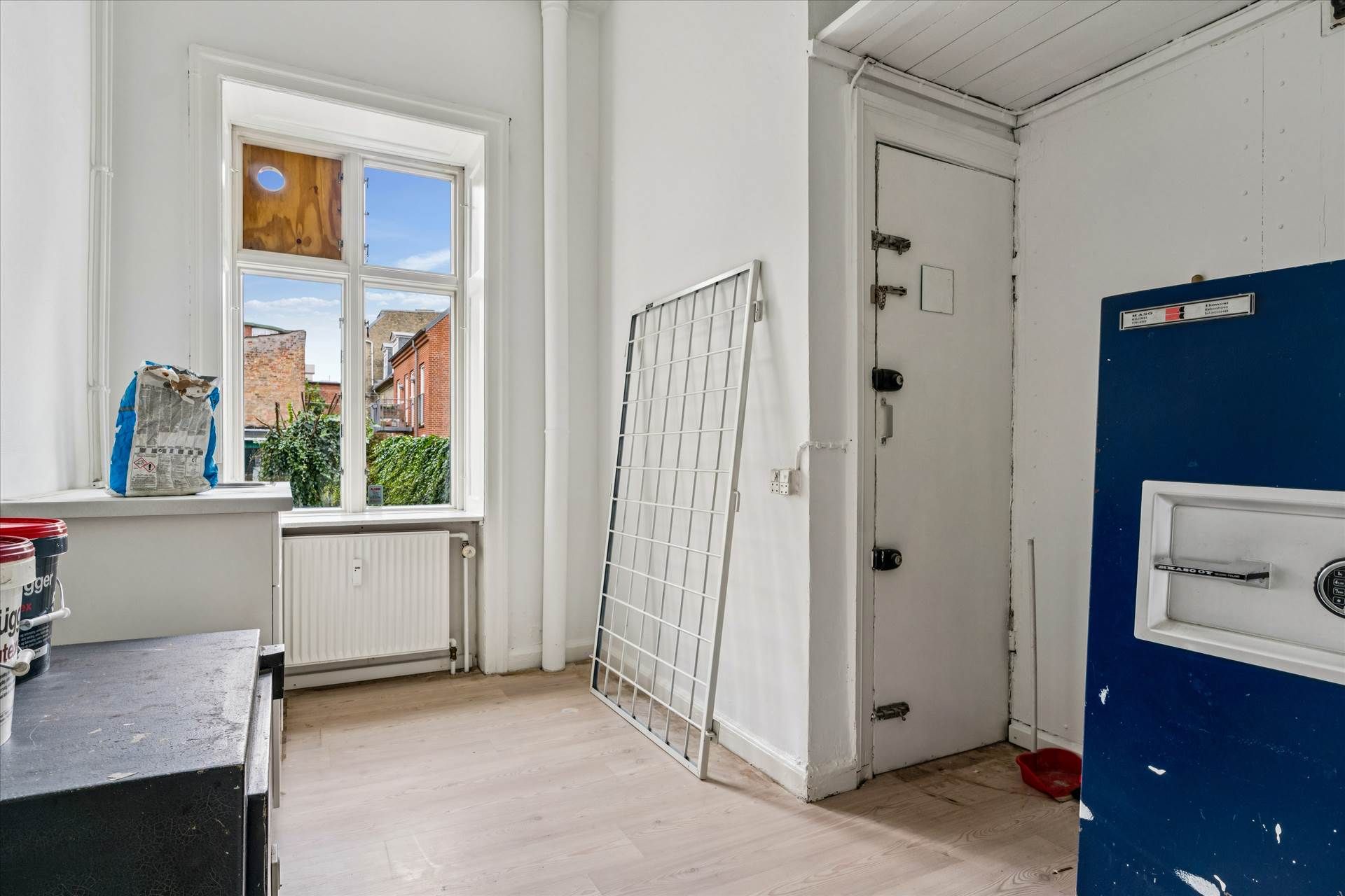 Renoveret butikslokale med stor synlighed, vinduer, radiator, hvid maling og metallisk dør