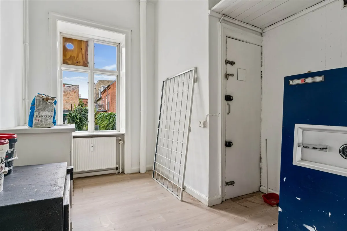 Renoveret butikslokale med stor synlighed, vinduer, radiator, hvid maling og metallisk dør