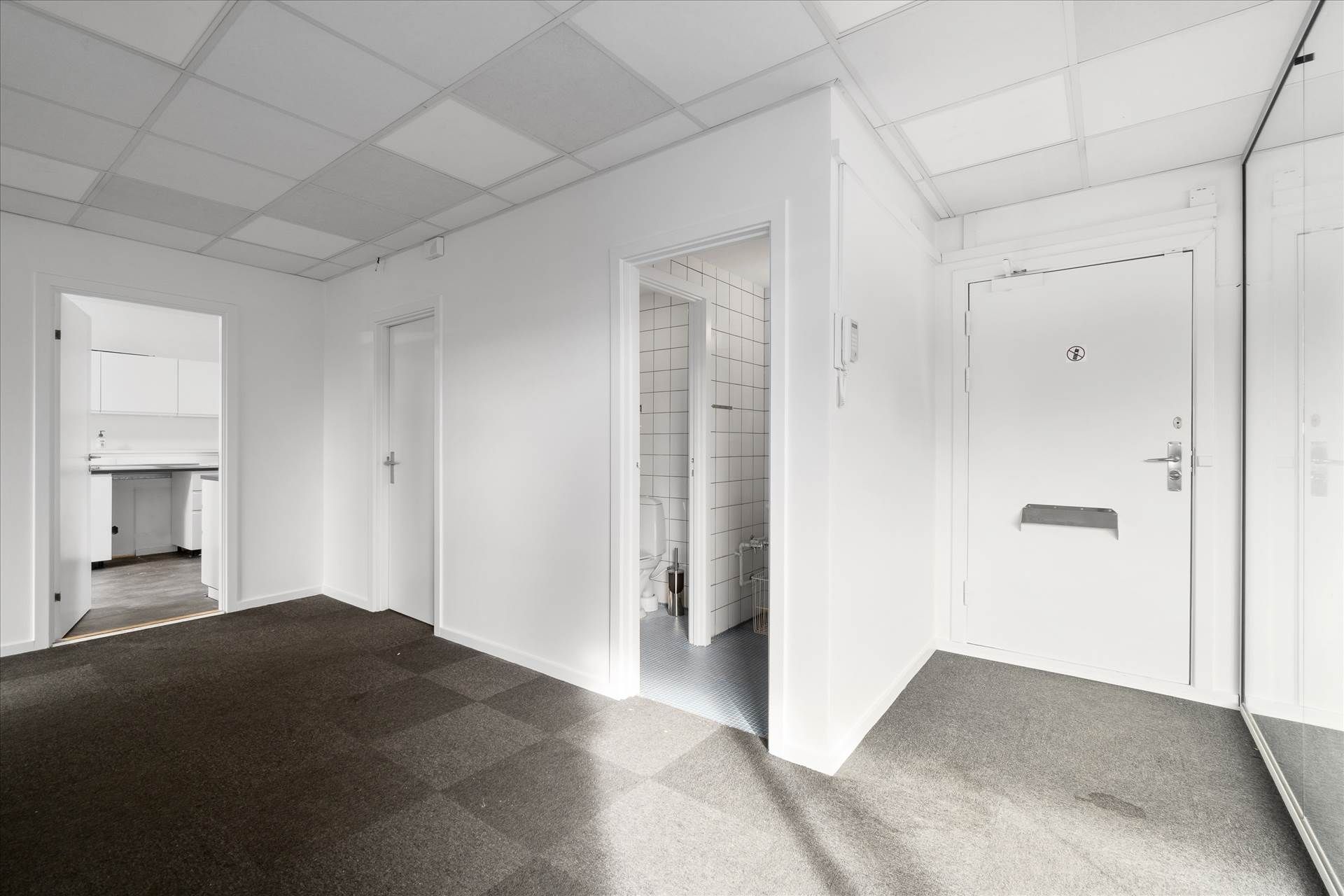 Velindrettet kontor med hvide vægge og gulve samt hvide døre og lofter