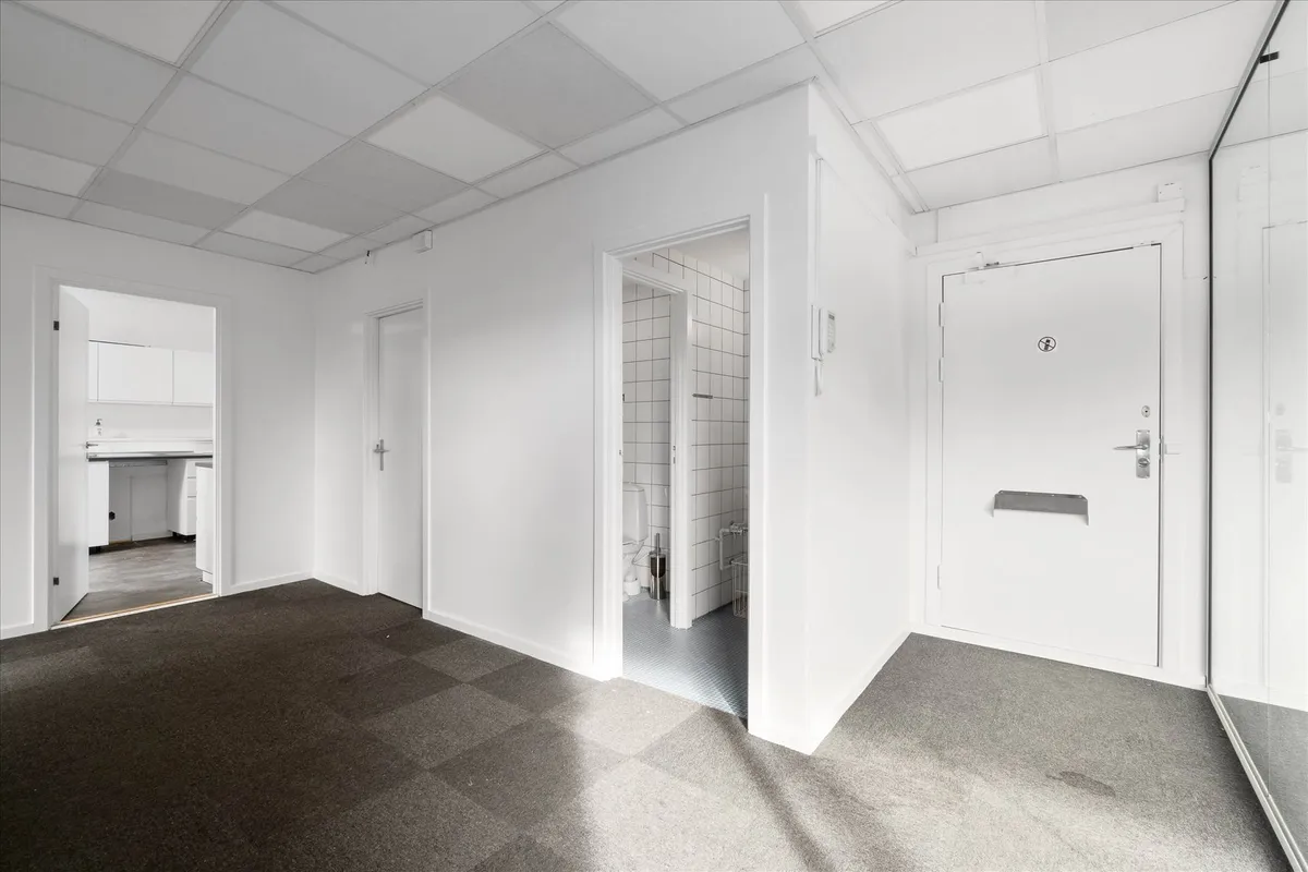 Velindrettet kontor med hvide vægge og gulve samt hvide døre og lofter