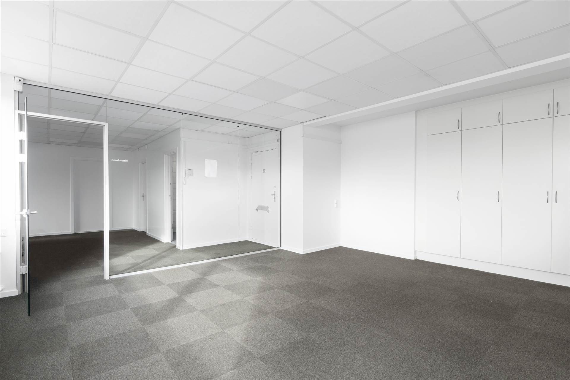 Velindrettet og charmerende kontorrum med hvide vægge og loft, glasdøre og gulvbelægning af grå karper. Værelset er tomt og