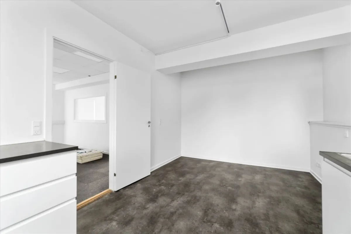 Moderne interiør med hvide vægge og gulv, minimalistisk design med åbne døre og hjørne. Højloftet med hvide kantprofiler og