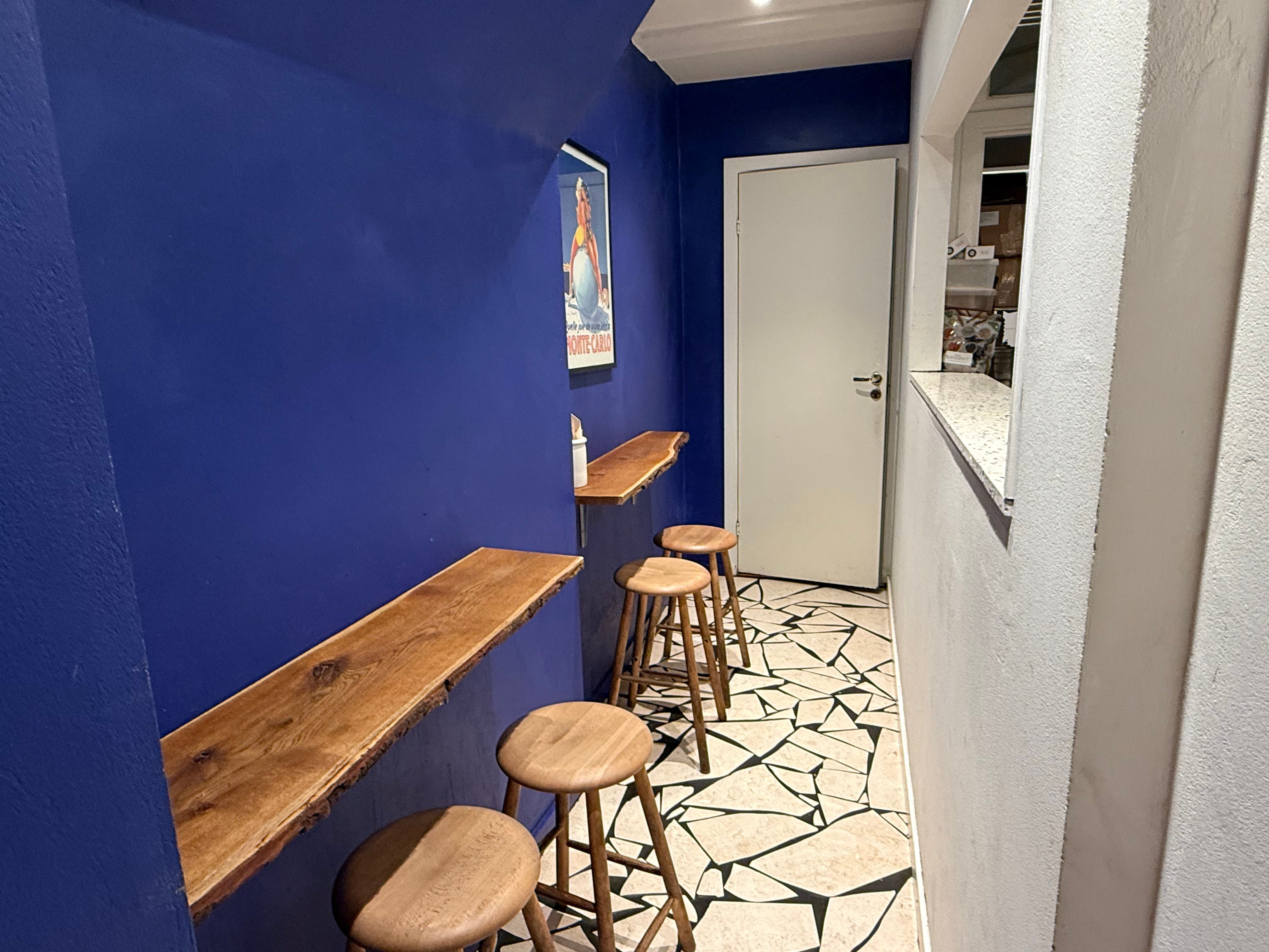 En lille hyggeligt stue med fire træstole, et bord og en væg med et kunstværk