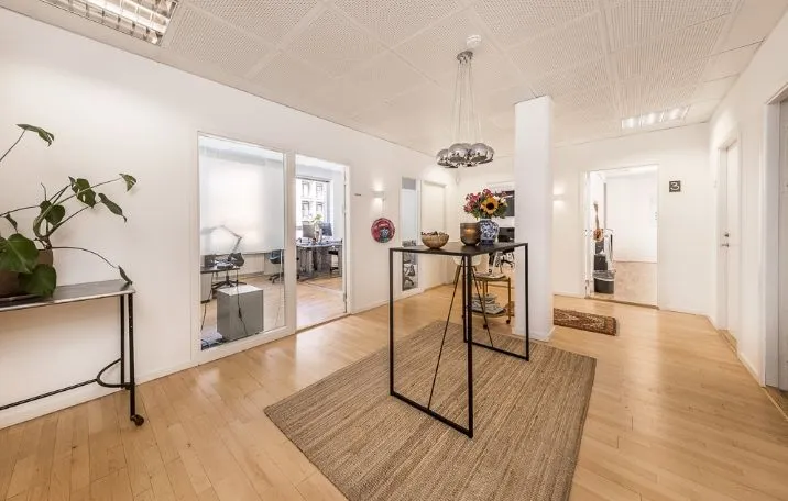 Kontorområde med højloftede rum og lyse lofter Store spejle og moderne møbler Forskellige kontormøbler og computere