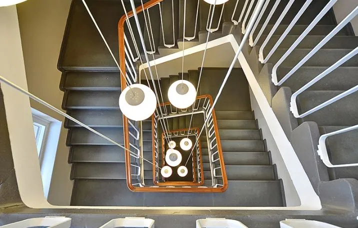 Et moderne trappeforløb med lysekroner, hvidt håndtag og slanke gulve i Frederiksstaden