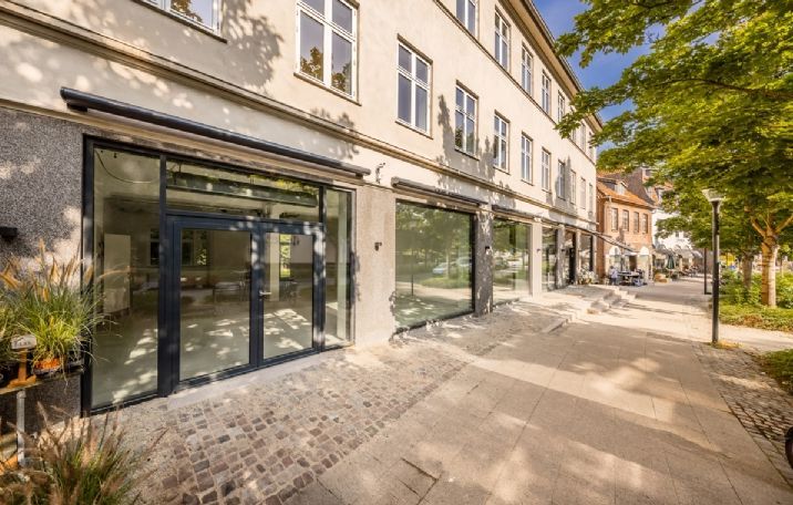 Butikslejemål med 120 m² i stueplan og 91 m² kælder i Holte. Væggene er beklædt med gult murværk.